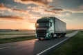 Green truck drives on asphalt road in rural landscape, sunset Royalty Free Stock Photo