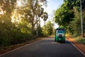 A green tuktuk rickshaw zooms through country lanes around Anu