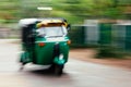 A green tuktuk rickshaw zooms through the street in Anuradhapu