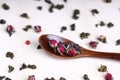 Green twisted tea leaves in clay cups with dried roses. Chinese oolong is scattered on the table in large quantities Royalty Free Stock Photo