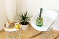 Green ukulele on a chair in a studio with a table and potted plant Royalty Free Stock Photo