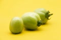 green unripe tomato isolated on yellow background Royalty Free Stock Photo