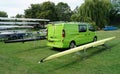 Green van parked on grass and racing boats on stands at regatta