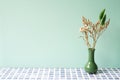 Green vase of dry flower on blue tile table. mint wall background Royalty Free Stock Photo