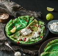 Green Vegan Crepes With Spinach Or Pancakes With Cottage Cheese, Pomegranate, Nuts And Spinach Leaves On Black Plate Over Dark