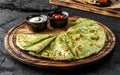 Green vegan crepes with spinach on plate served with cream or gem on dark background, close up view. Pancake week or Shrovetide.