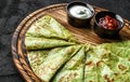 Green vegan crepes with spinach on plate served with cream or gem on dark background, close up view. Pancake week or Shrovetide.