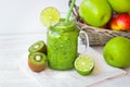 Green vegetable and fruit smoothie, basket with apples, kiwi, lime,sunlight