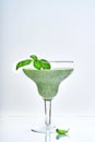 Green vegetable juice or smoothie garnished with leaf of fresh basil in coctail margarita glass isolated on white