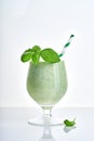 Green vegetable juice or smoothie garnished with leaf of fresh basil in coctail margarita glass isolated on white