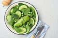 Green vegetable salad with spinach, avocado, green peas and olive oil in bowl on light gray slate, stone or concrete background. Royalty Free Stock Photo