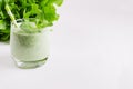 Green vegetable smoothie in glass with straw, mint twig, lettuce, copy space, closeup.