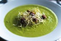 Green vegetable soup decorated with fresh soya and nuts