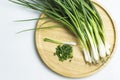 Green vegetable spring onions in a wooden dish. Top view.