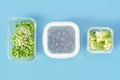 Green vegetables and berries in glass lunch boxes on blue background close-up. Royalty Free Stock Photo