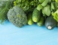 Green vegetables on a blue wooden background. Parsley, spinach, cucumber, broccoli, dill and zucchini. Top view. Green vegetables
