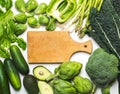Green vegetables and herbs assortment around wooden cooking board. Royalty Free Stock Photo
