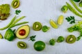 Green vegetables and herbs assortment around wooden cooking board on a white background. Fresh Healthy food. Top view, copy space Royalty Free Stock Photo