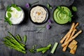 Green vegetables raw snack board with various dips. Yogurt sauce or labneh, hummus, herb hummus or pesto with crackers, grissini Royalty Free Stock Photo