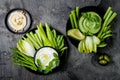 Green vegetables snack board with various dips. Yogurt sauce or labneh, hummus, herb hummus or pesto with fresh vegetables.