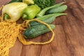 Green vegetables of zucchini, okra, cucumbers, bell pepper and a bunch of parsley lie next to a yellow string bag on a brown Royalty Free Stock Photo