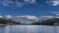 Green vegetation grows on the shores of a beautiful calm lake. Ripples and highlights on the blue water. Royalty Free Stock Photo