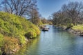 Green vegetation reflects on water in Malmo Kungsparken sea canal while canoes and kayaks are docking or mooring by a wooden jetty