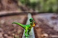 Green Velociraptor dinosaur walking on rail railroad tracks