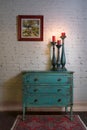 Green vintage cabinet, candlesticks and hanged painting on bricks wall