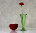 Green vintage vase and red artificial flower.