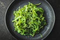 Green wakame. Seaweed salad on black plate