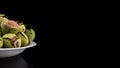 Green walnuts in the plate on a black background, cracked peel, fresh kernel, copyspace Royalty Free Stock Photo