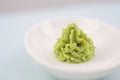 Green wasabi sauce or paste in bowl, with chopsticks or spoon over plain colourful background. selective focus Royalty Free Stock Photo