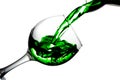 Green water pours into a glass on a white background