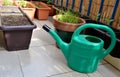 Green watering can and seedlings in flower boxes as a part of urban garden on the balcony