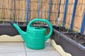 Green watering can and seedlings (tomato, onion) in flower boxes as part of urban garden on the balcony Royalty Free Stock Photo