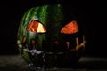 Green watermelon burns with fiery flame on the scary holiday halloween