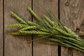 Green wheat branches from the field lie on an old wooden table