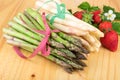 Green white asparagus with fresh strawberries on bright wood. Vegan food, vegetarian and healthy cooking concept. Royalty Free Stock Photo