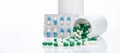 Green-white capsule pills on blur blister pack of blue-white capsule pills and drug bottle. Pills spread out of plastic bottle. Royalty Free Stock Photo