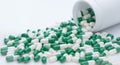 Green and white capsule pills spilled out of a white plastic bottle. Pharmaceutical industry. Prescription drug. Healthcare and Royalty Free Stock Photo