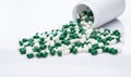 Green and white capsule pills spilled out of a white plastic bottle. Pharmaceutical industry. Prescription drug. Healthcare and Royalty Free Stock Photo