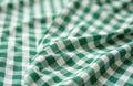 Green and white checkered fabric tablecloth ripples gently. Textured textile surface creates a classic gingham pattern, perfect Royalty Free Stock Photo