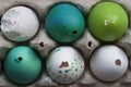 Green and white Easter eggs in egg carton. Candle egg, gypsum egg, poultry egg, ground. Close up. Rustical flat lay