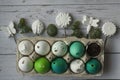 Green and white Easter eggs in egg carton. Candle egg, gypsum egg, poultry egg, ground on wooden background. Rustical flat lay