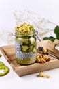 Green fruit smoothie layered in glass with chia seed pudding topped with star shaped banana and kiwi slices on wooden tray Royalty Free Stock Photo