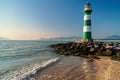 Coastal Beacon: Green and White Lighthouse on Rocky Shoreline Royalty Free Stock Photo