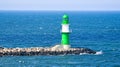 green white lighthouse on the Warnow River in Rostock on the Baltic Sea. Waves on the stone edge Royalty Free Stock Photo