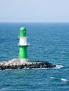 green white lighthouse on the Warnow River in Rostock. Waves on the stone edge