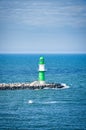 green white lighthouse on the Warnow River in Rostock. Waves on the stone edge